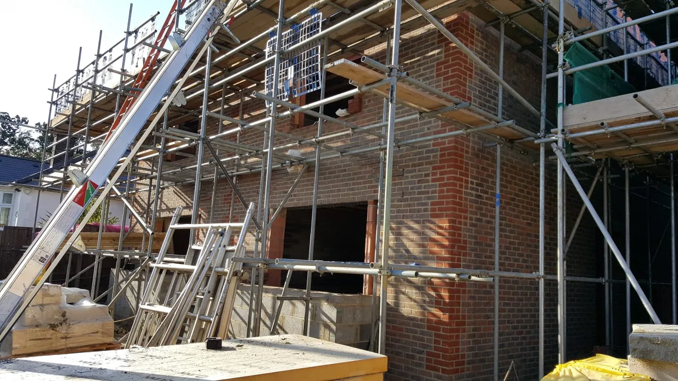 Two-storey brick and block extension rising inside scaffolding on a Brits site