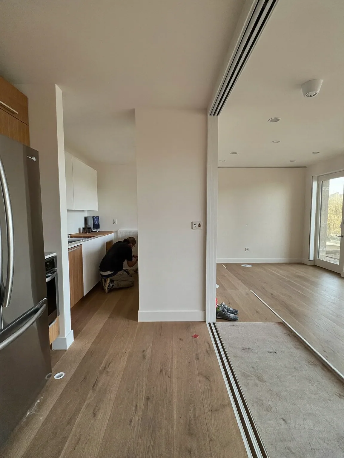 New kitchen units and engineered oak flooring being fitted in a bright open-plan room