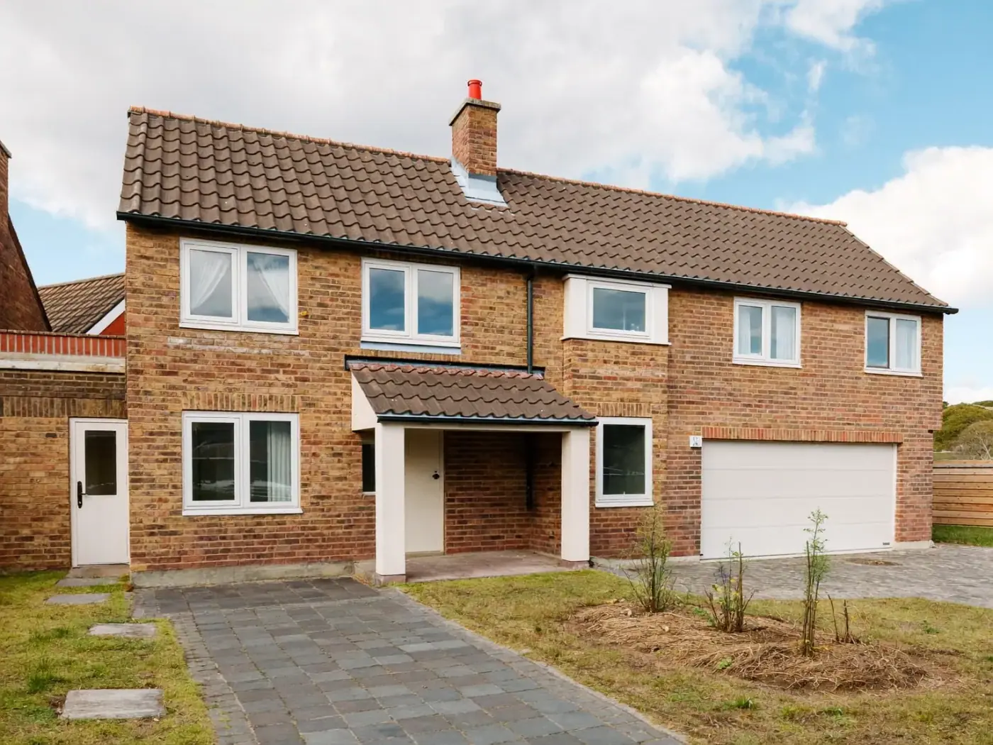 Detached two-storey brick house with a tiled roof, integral double garage and a paved path