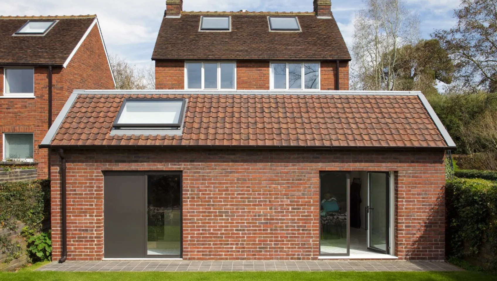 Single-storey brick rear extension with a pitched clay-tile roof, a roof window and sliding glass doors