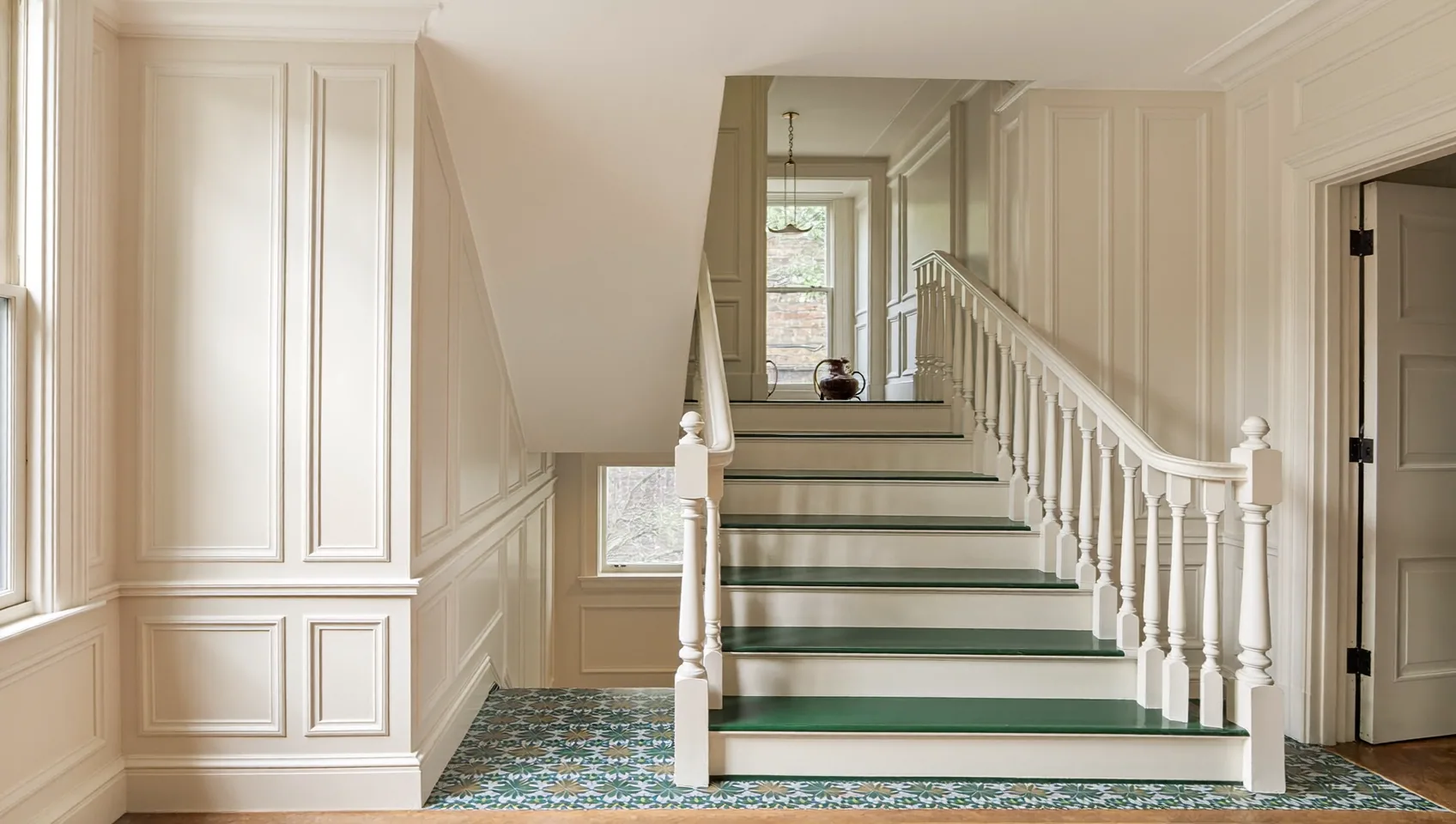 Panelled hallway and staircase with white balusters, green-painted treads and patterned floor tiles