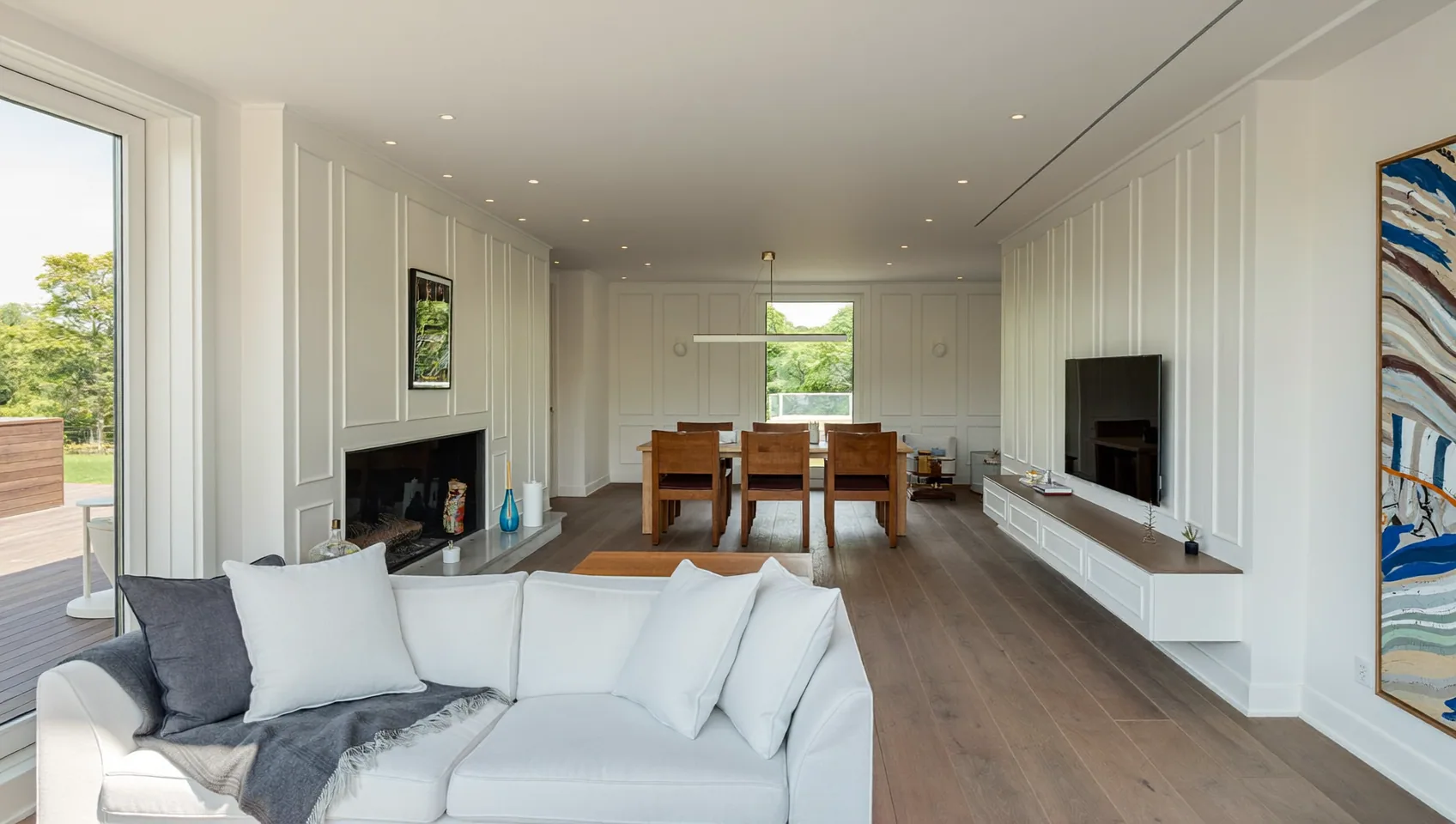 Renovated open-plan living and dining room with panelled walls, oak flooring and a white sofa