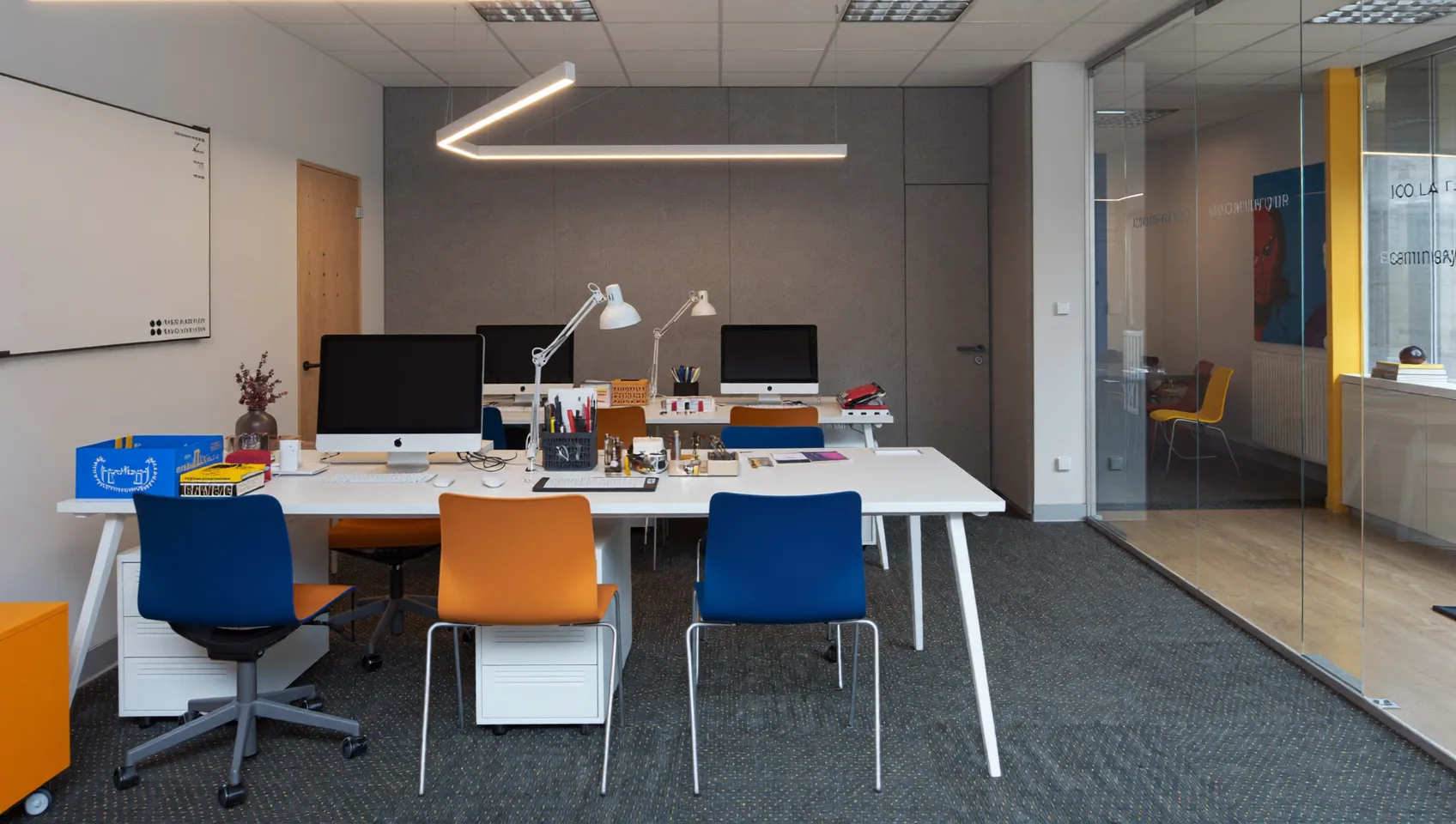 Office fit-out with white desks, monitors, bright task chairs and carpet tiles