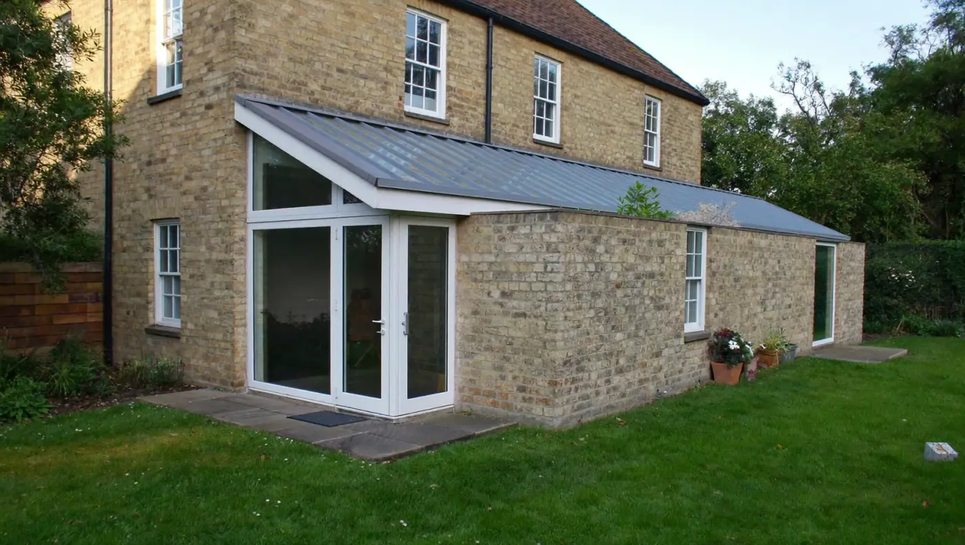L-shaped wraparound extension in matching stock brick with a sloping glazed side roof