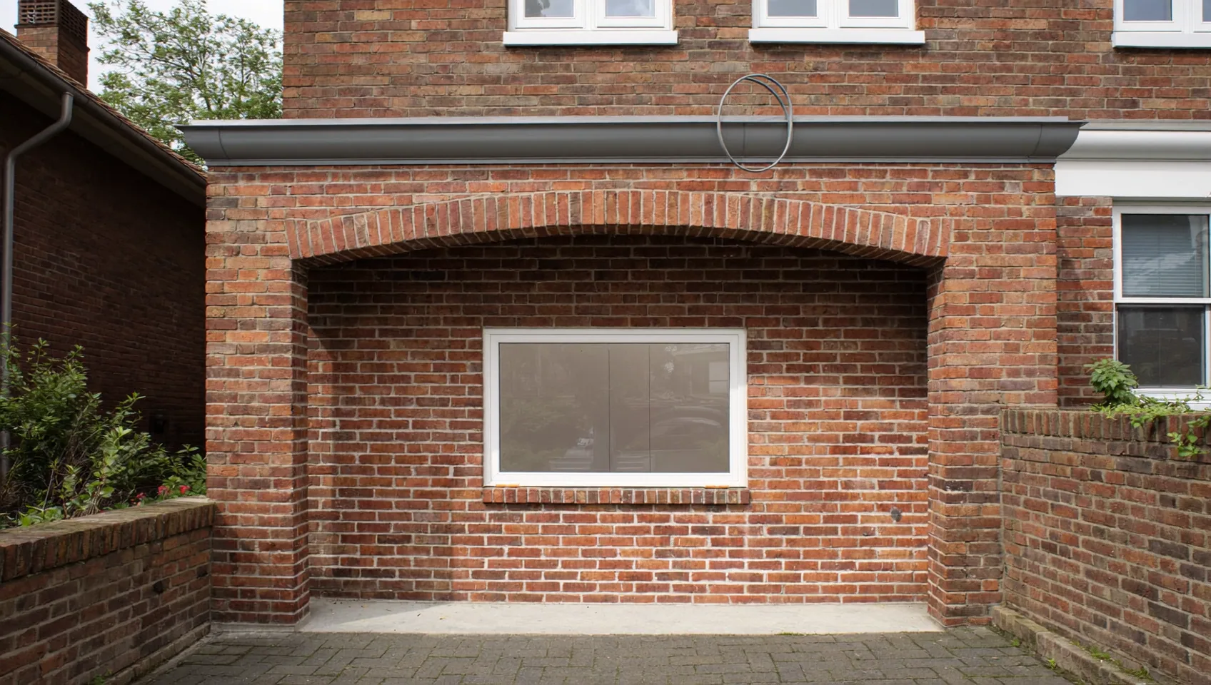 Garage opening infilled with brick and a new window set in an arched recess
