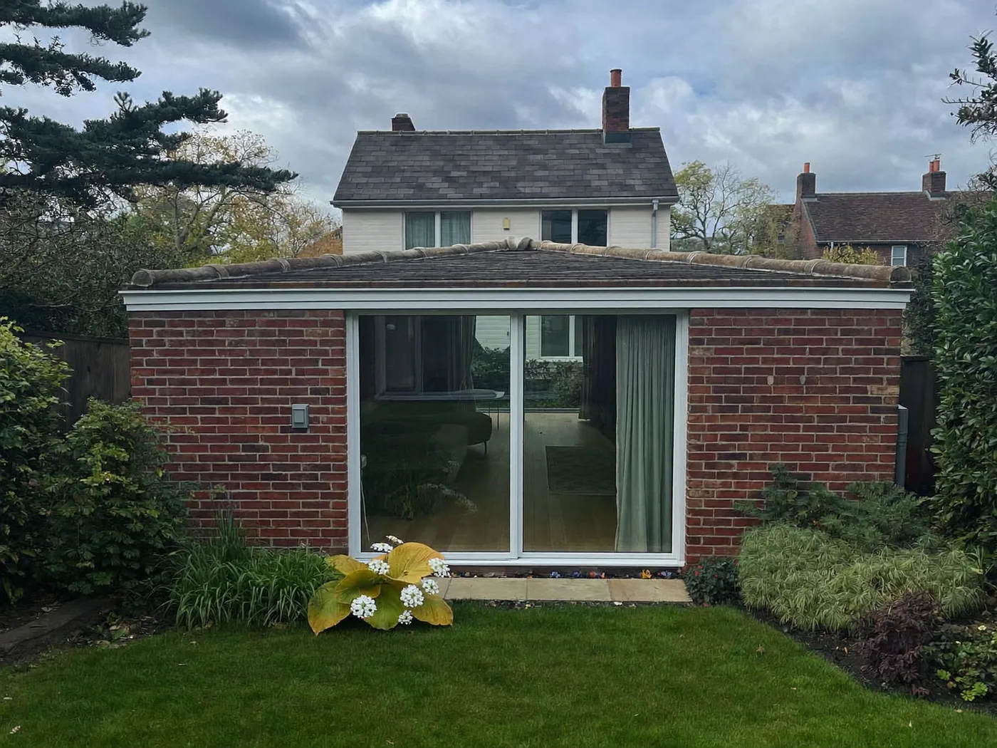 Amersham: single-storey brick rear extension with dark sliding doors onto a lawn