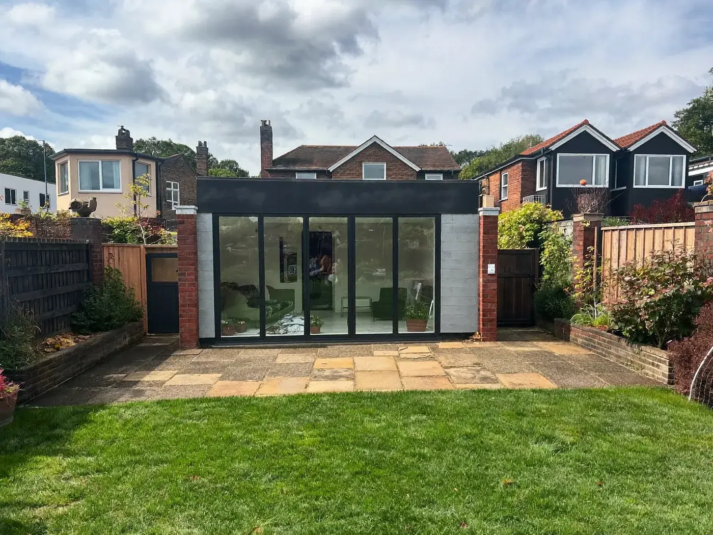 Barking & Dagenham: single-storey brick rear extension with dark sliding doors onto a lawn