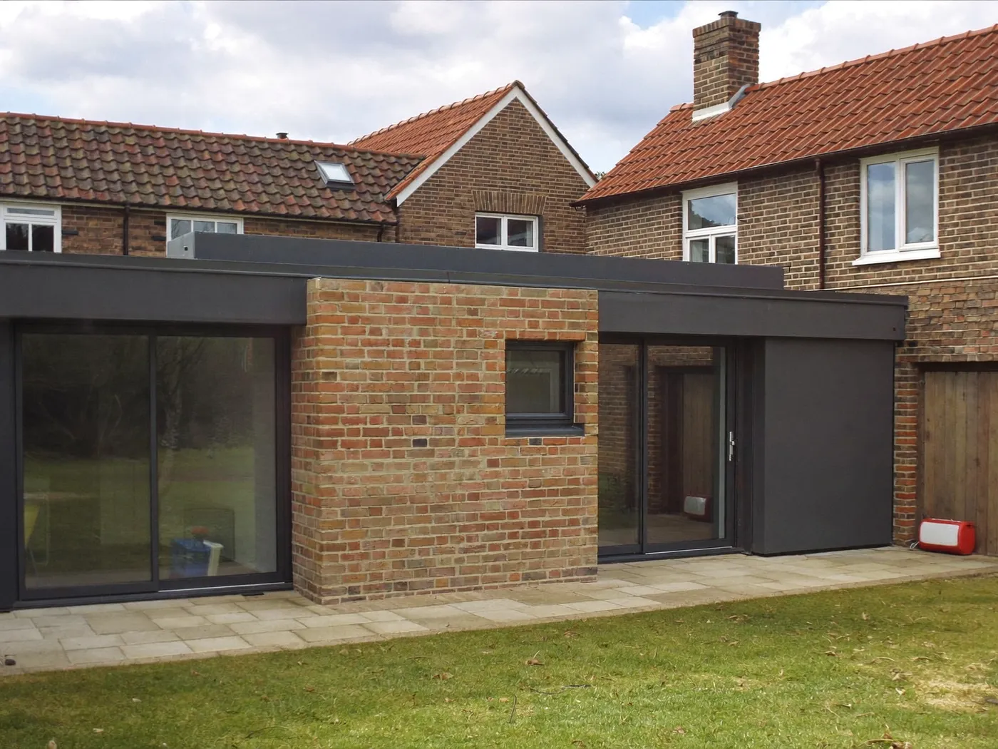 Borehamwood: single-storey brick rear extension with dark sliding doors onto a lawn