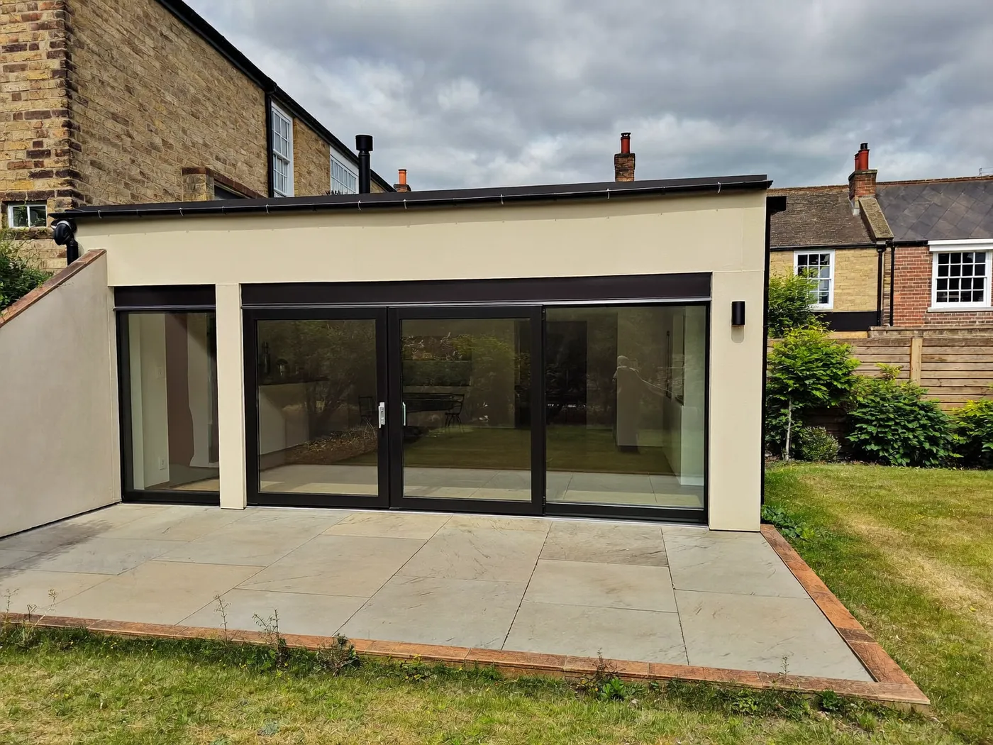 Bromley: single-storey brick rear extension with dark sliding doors onto a lawn