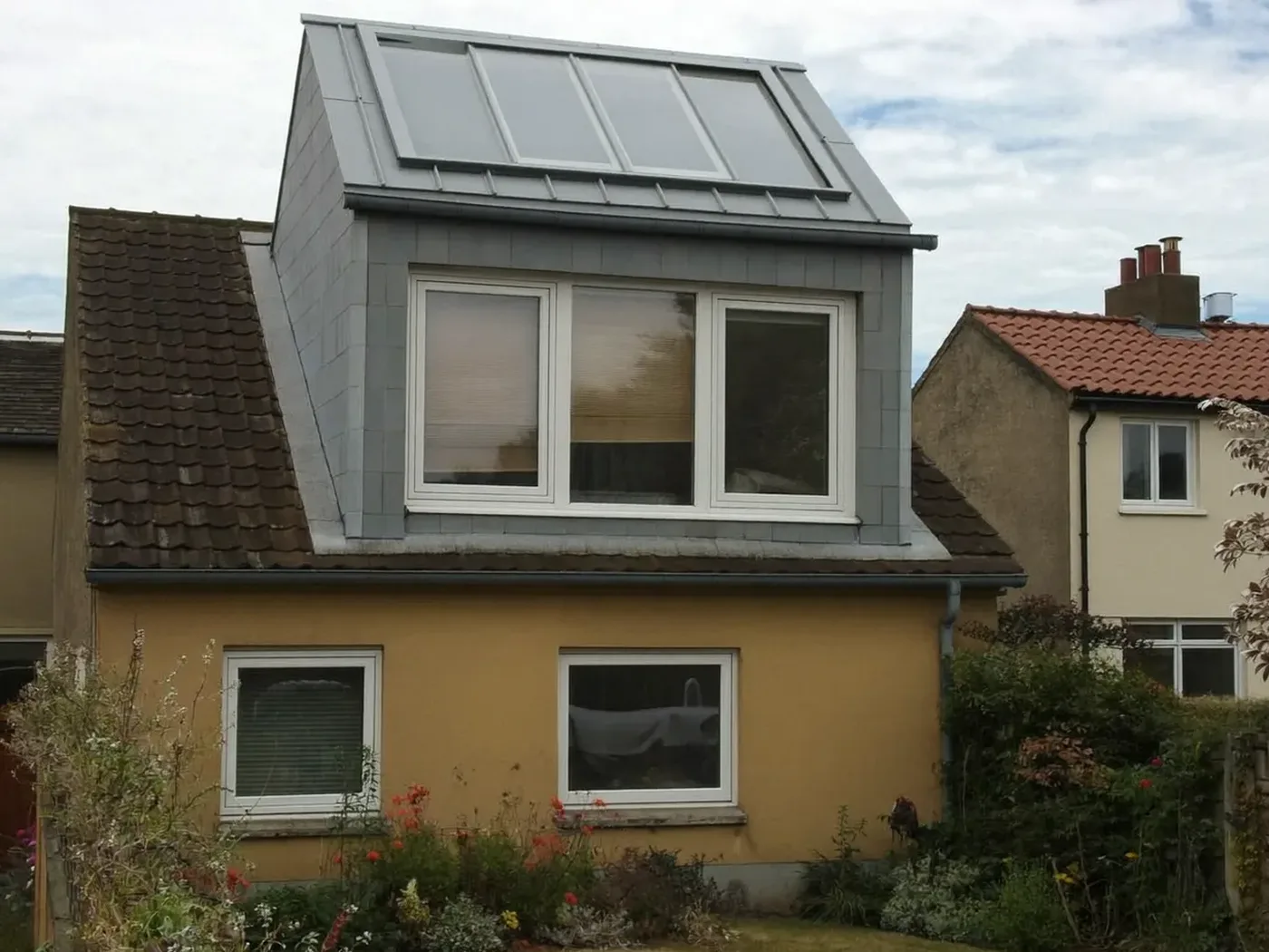 Bromley: grey-clad box dormer loft conversion on the rear roof of a house with white windows