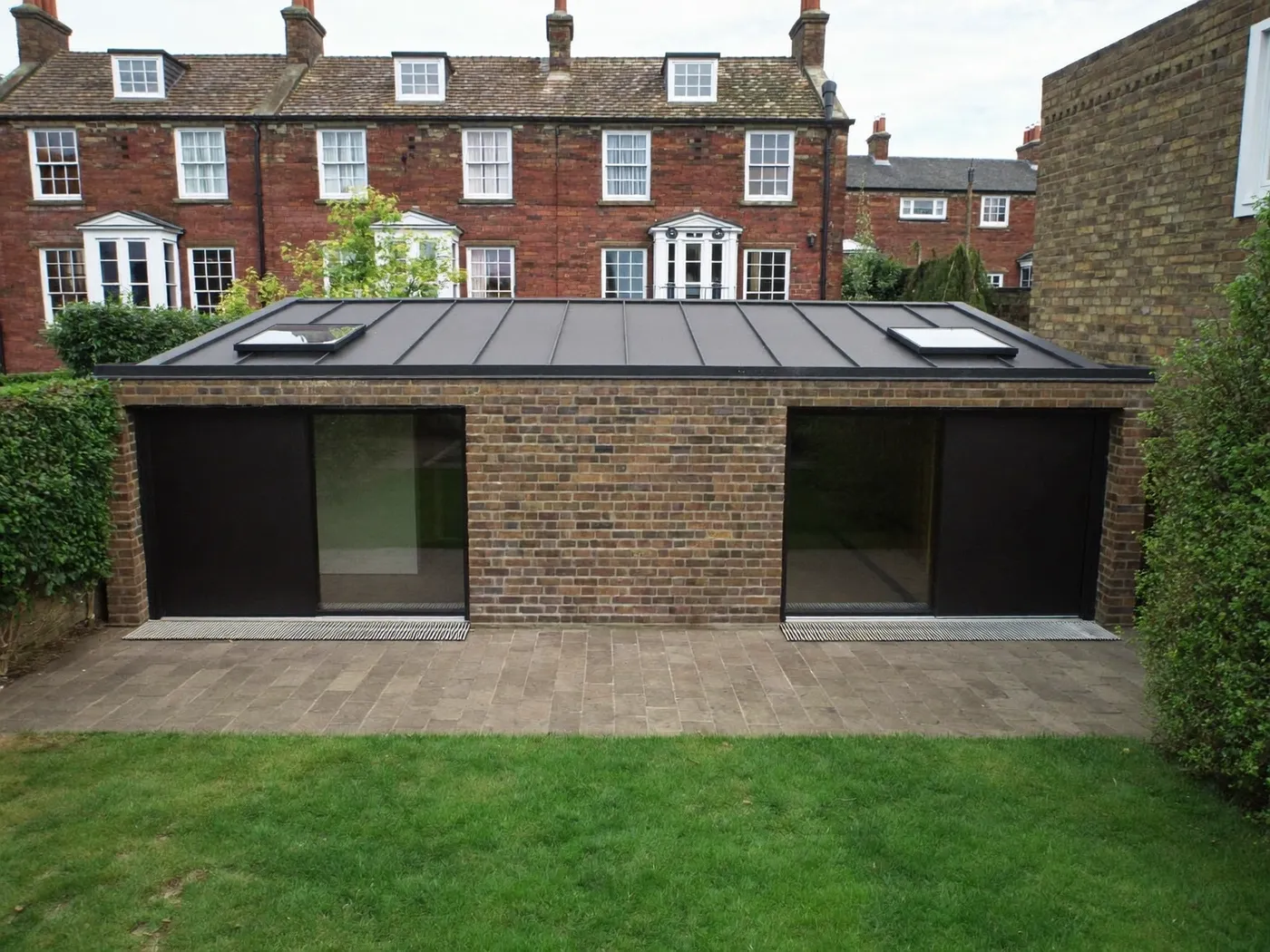 Croydon: single-storey brick rear extension with dark sliding doors onto a lawn