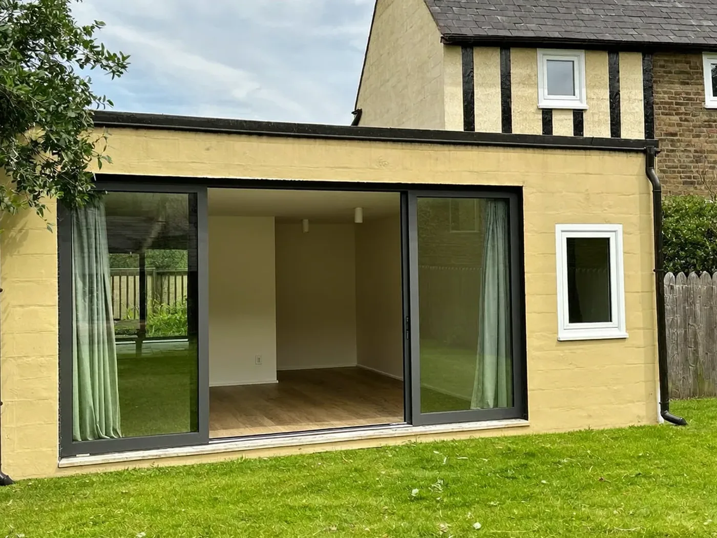 Essex: single-storey brick rear extension with dark sliding doors onto a lawn
