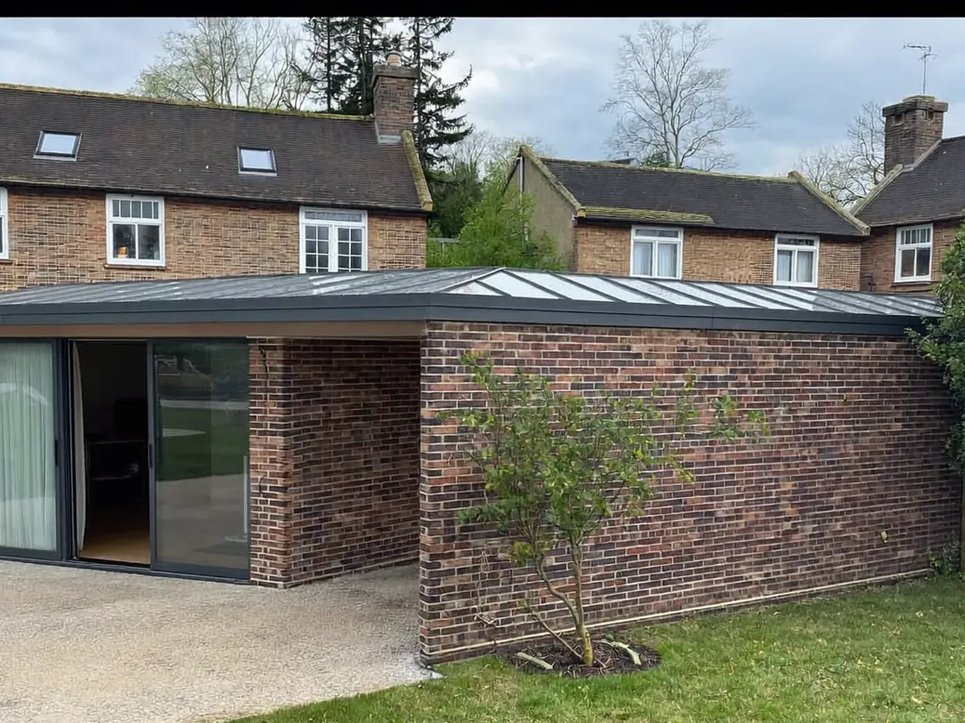 Essex: single-storey brick rear extension with dark sliding doors onto a lawn