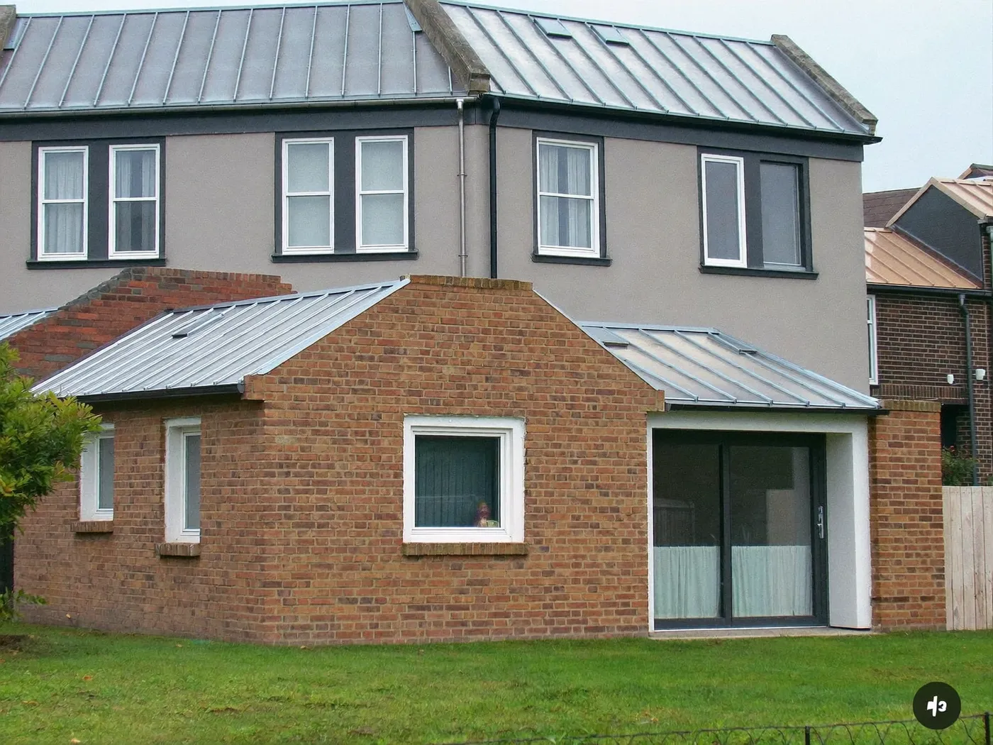 Gerrards Cross: L-shaped brick extension wrapping around the back and side of a house with dark sliding doors