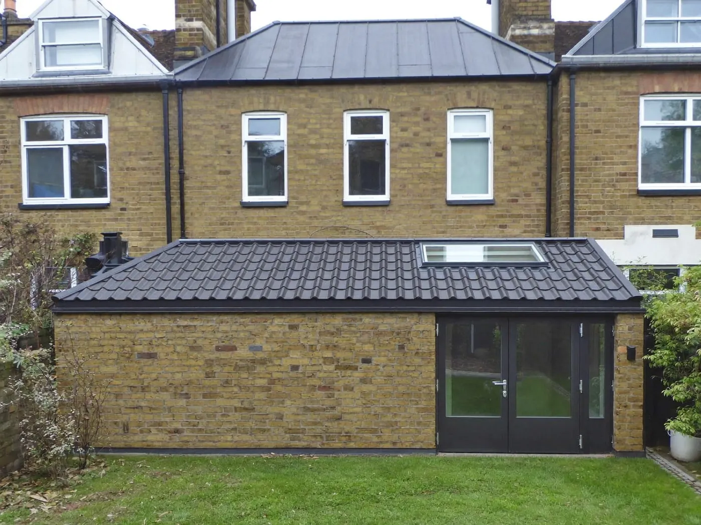 Hackney: brick side-return extension at the back of a terraced house with white French doors