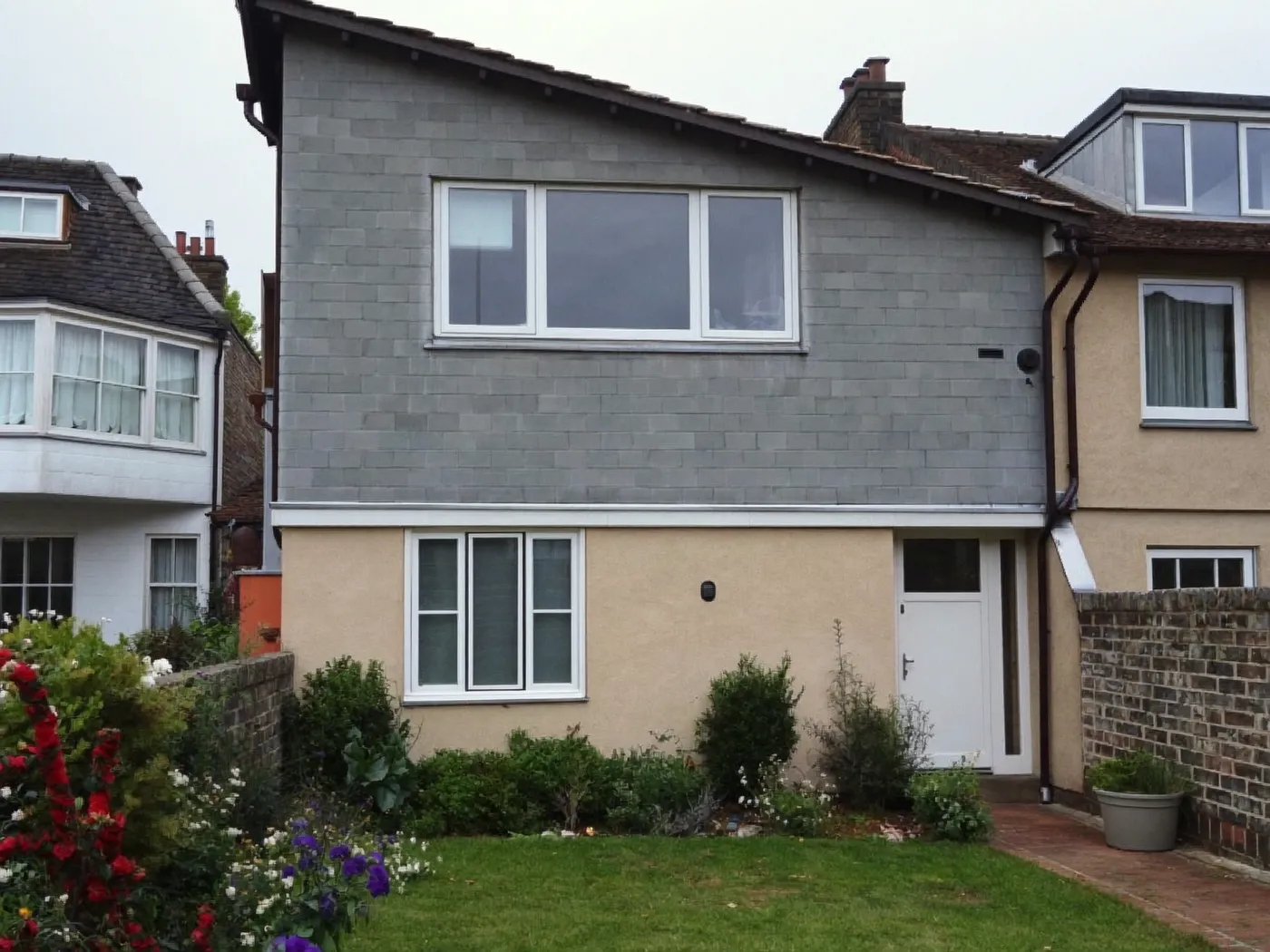 Semi-detached house with a grey-clad rear roof extension, white windows and a cottage garden