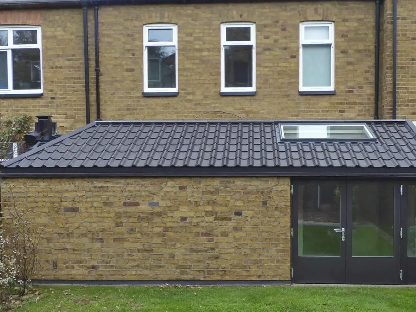 Haringey: brick side-return extension at the back of a terraced house with white French doors