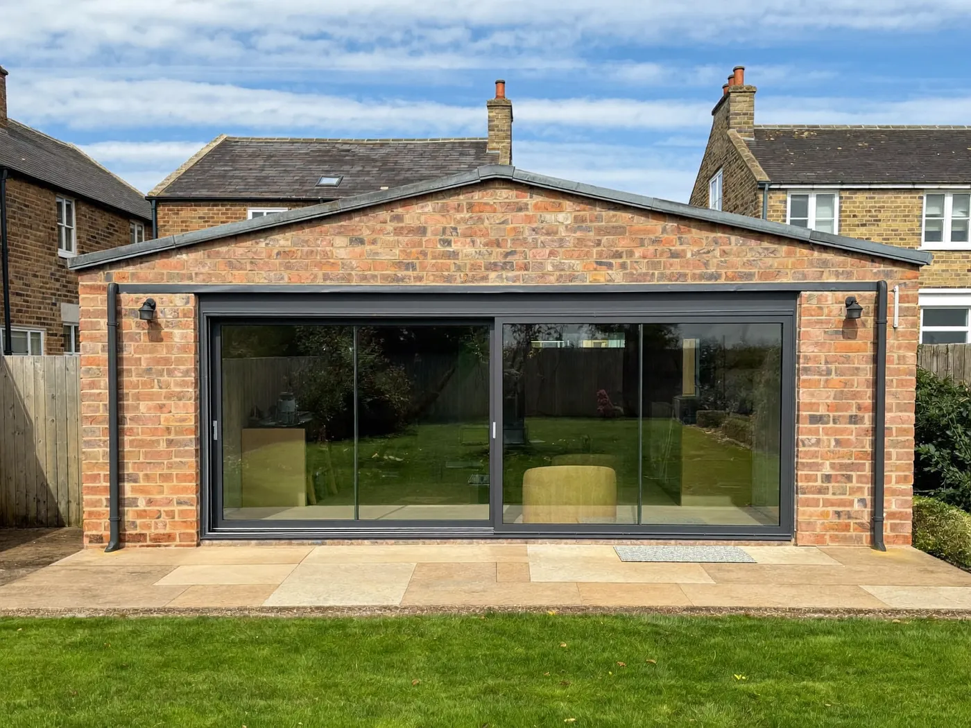 Harrow: single-storey brick rear extension with dark sliding doors onto a lawn