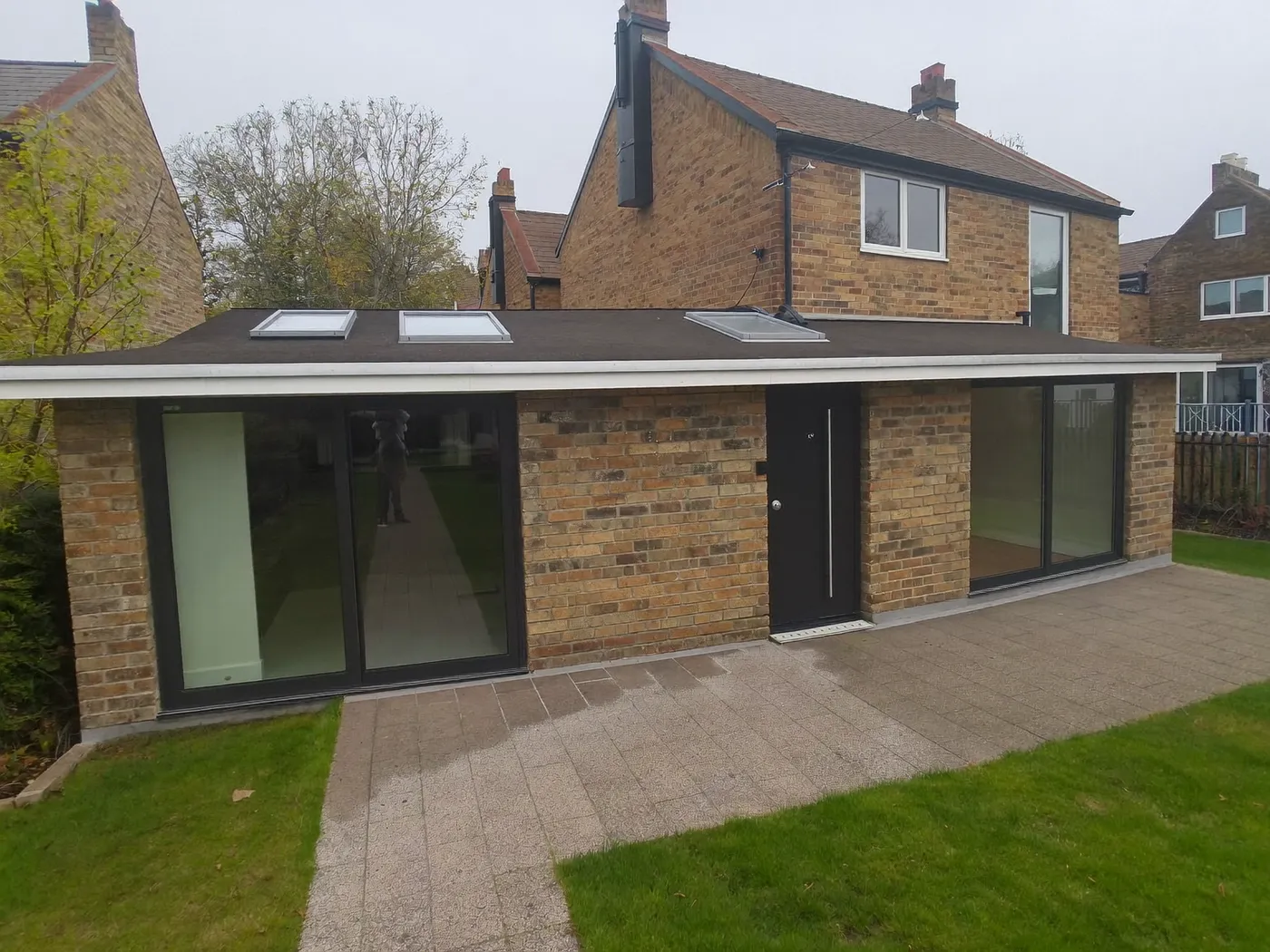 Hemel Hempstead: single-storey brick rear extension with dark sliding doors onto a lawn