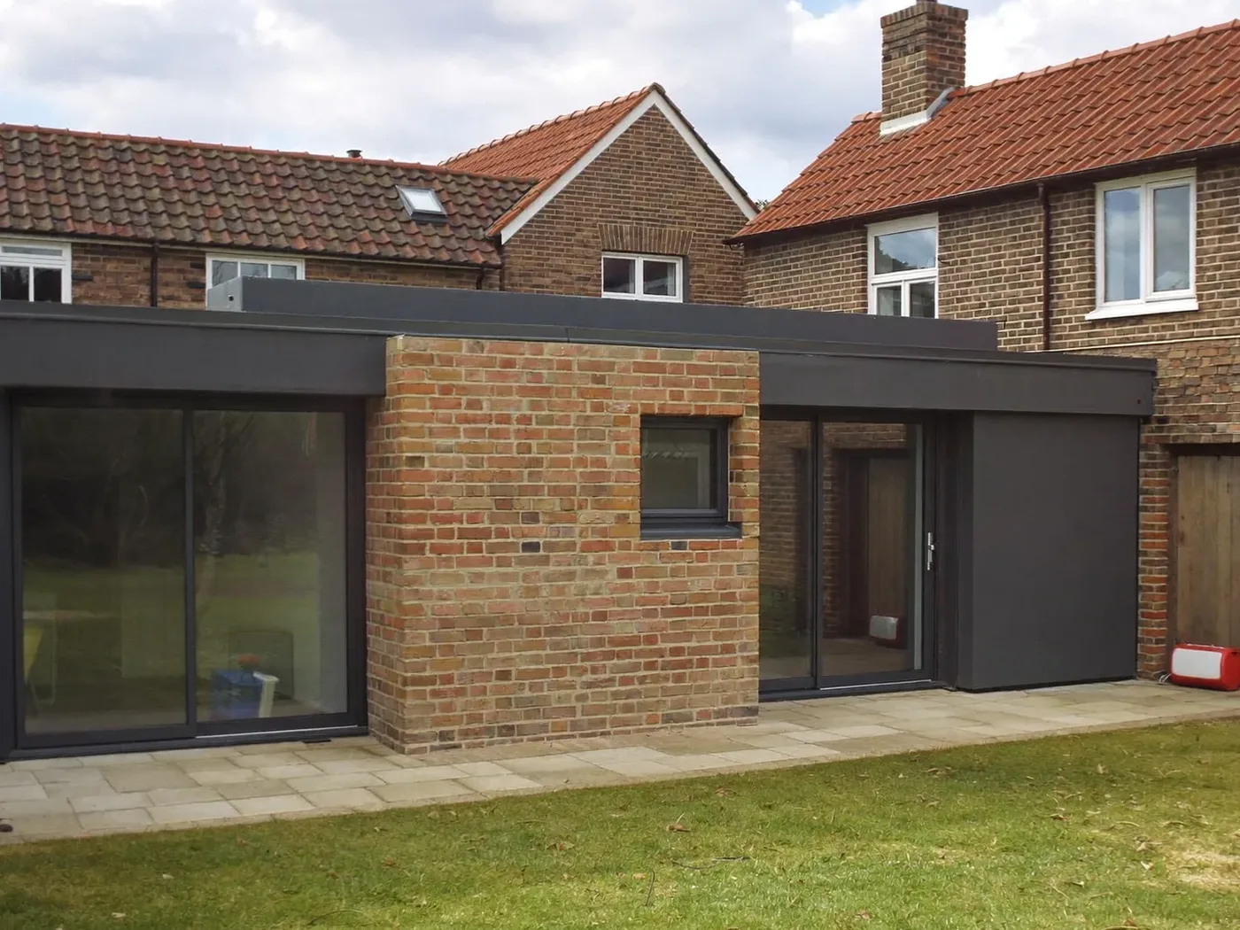 Hemel Hempstead: single-storey brick rear extension with dark sliding doors onto a lawn