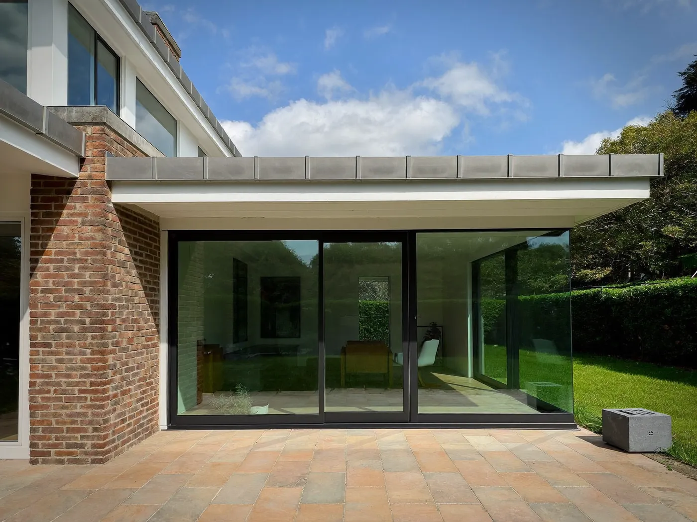 Hertfordshire: single-storey brick rear extension with dark sliding doors onto a lawn