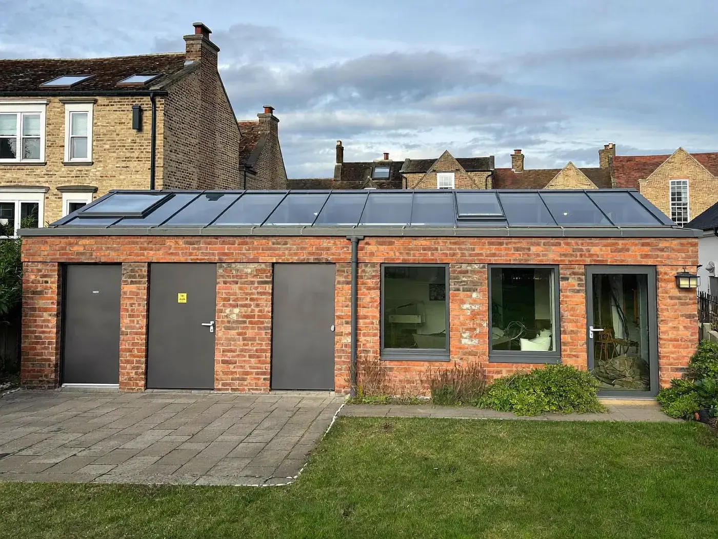 High Wycombe: single-storey brick rear extension with dark sliding doors onto a lawn