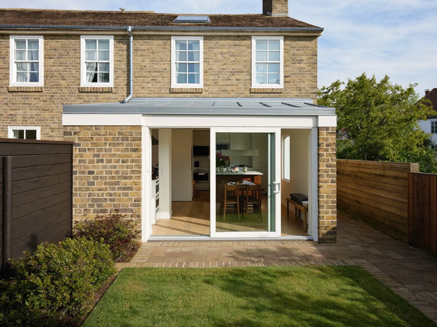 Kingston: single-storey brick rear extension with dark sliding doors onto a lawn