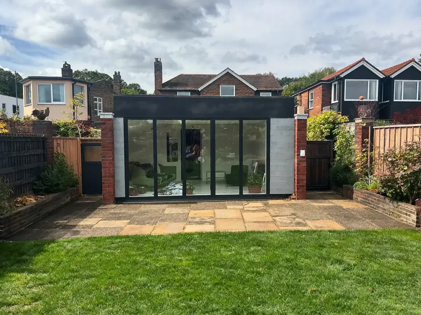 Lambeth: single-storey brick rear extension with dark sliding doors onto a lawn