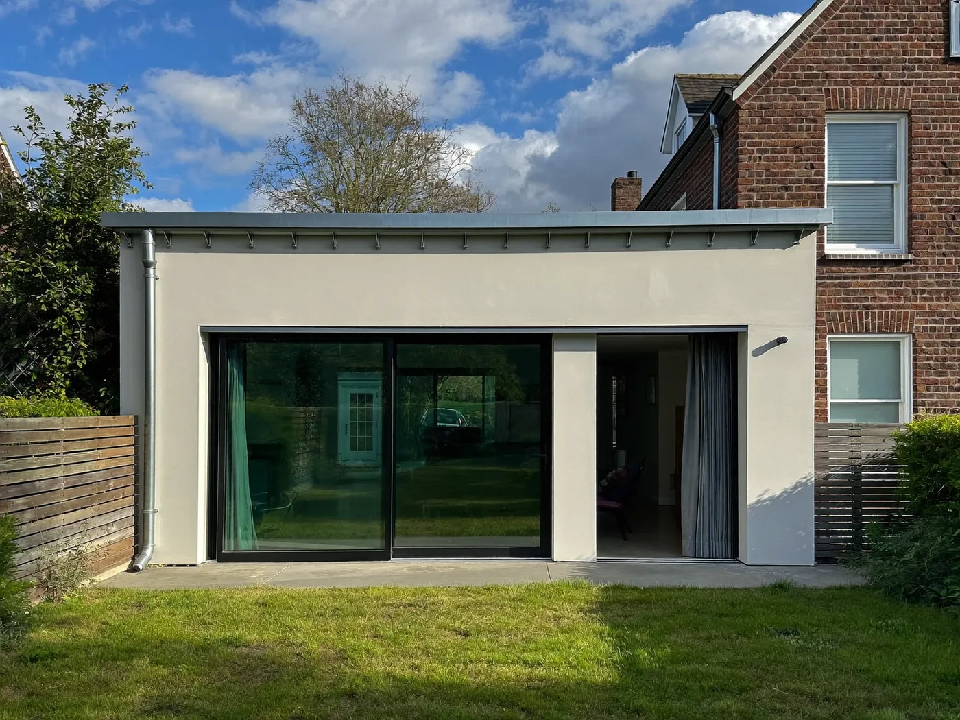 Maidenhead: single-storey brick rear extension with dark sliding doors onto a lawn