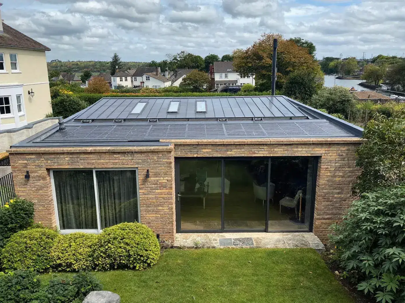 Maidenhead: L-shaped brick extension wrapping around the back and side of a house with dark sliding doors