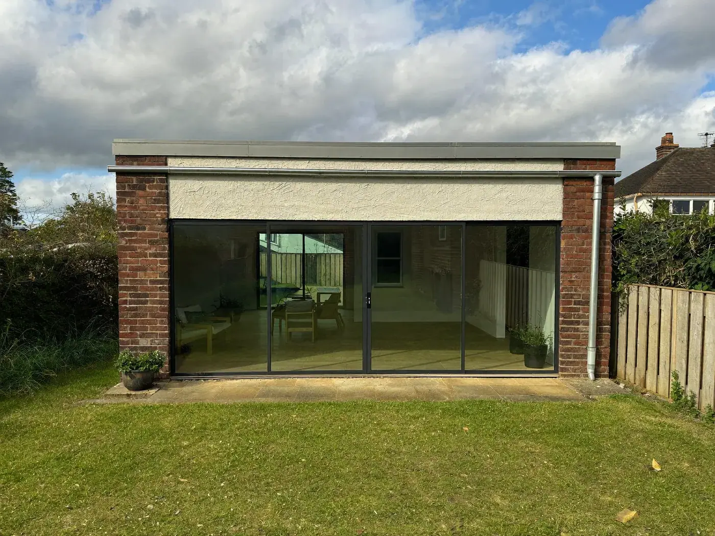 Merton: single-storey brick rear extension with dark sliding doors onto a lawn