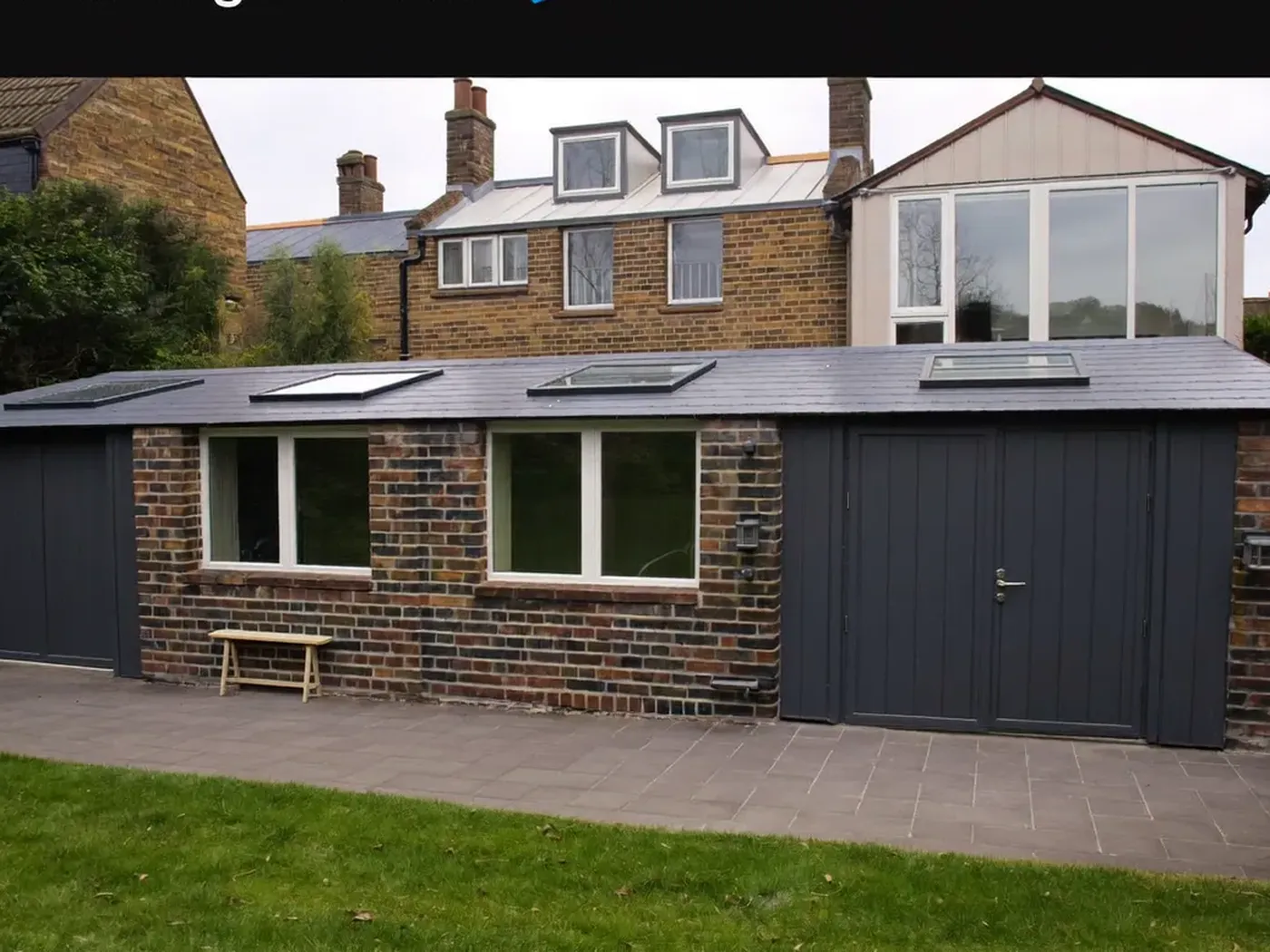 Merton: single-storey brick rear extension with dark sliding doors onto a lawn