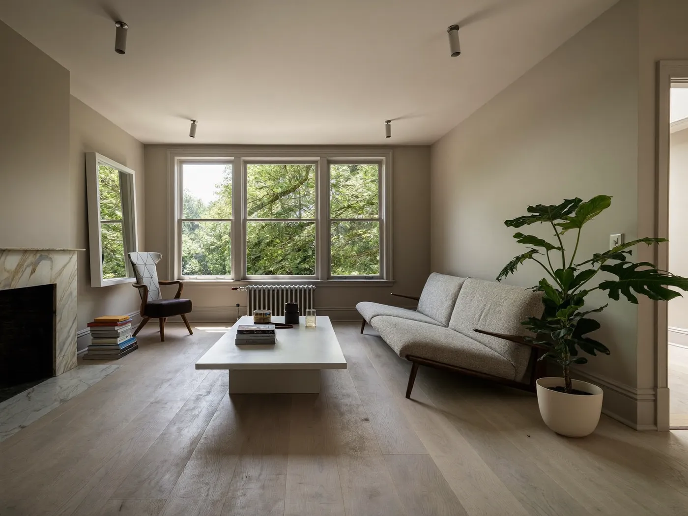 Spacious living room with an oak floor, white sofa, a plant and large sash windows