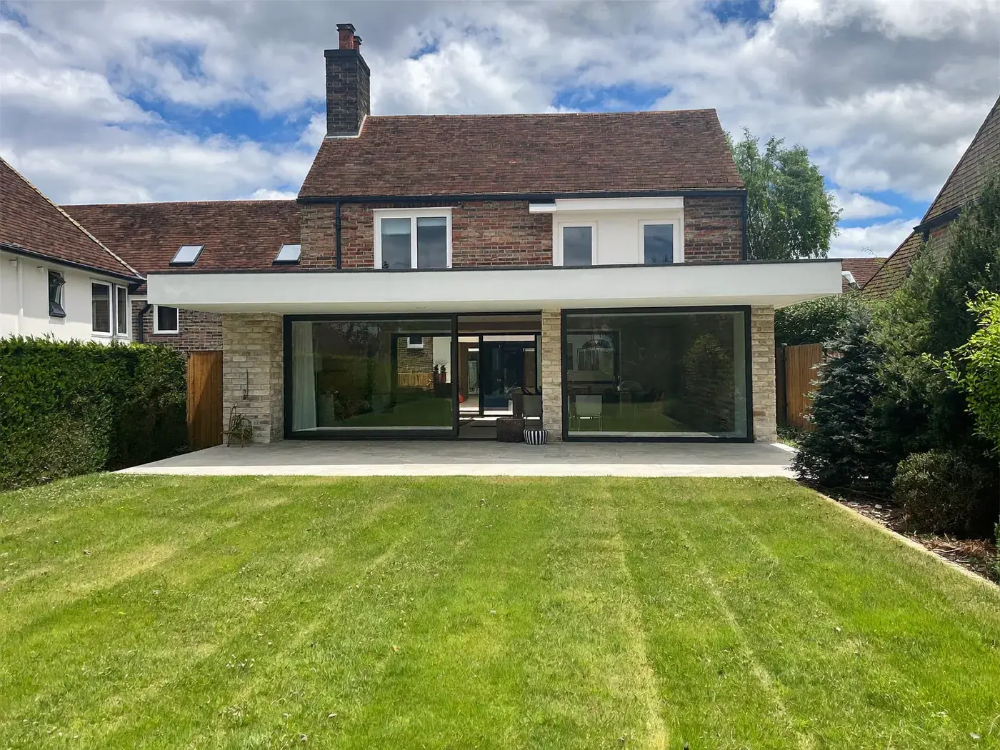 Potters Bar: single-storey brick rear extension with dark sliding doors onto a lawn