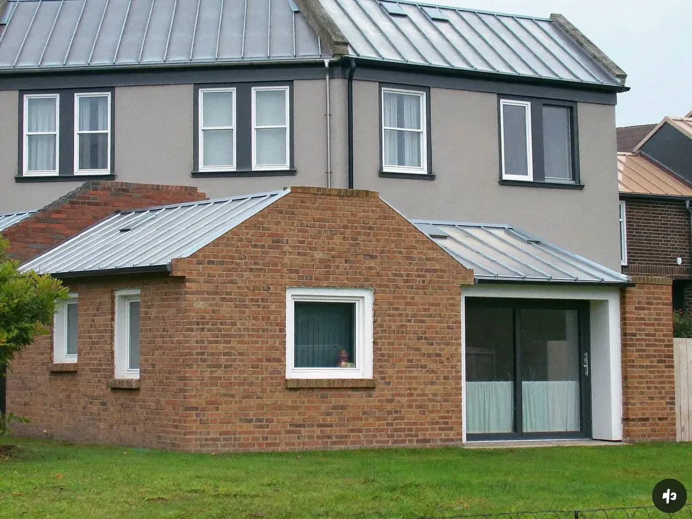 Potters Bar: L-shaped brick extension wrapping around the back and side of a house with dark sliding doors