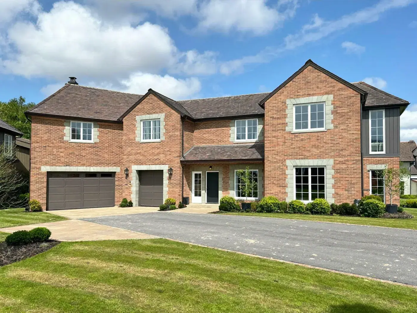 Large detached red-brick house with stone window surrounds, a double garage and a tarmac driveway