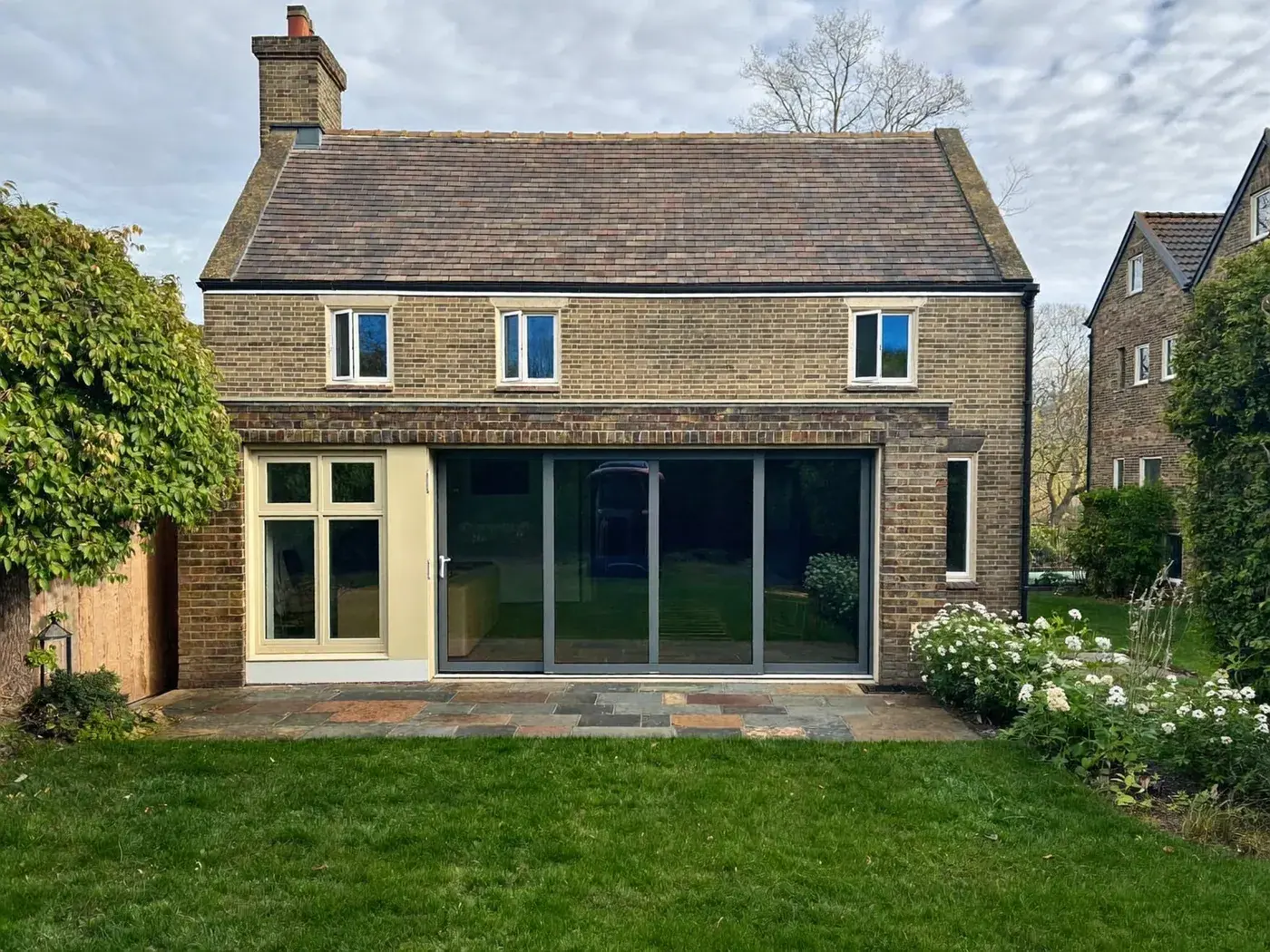 Rickmansworth: single-storey brick rear extension with dark sliding doors onto a lawn