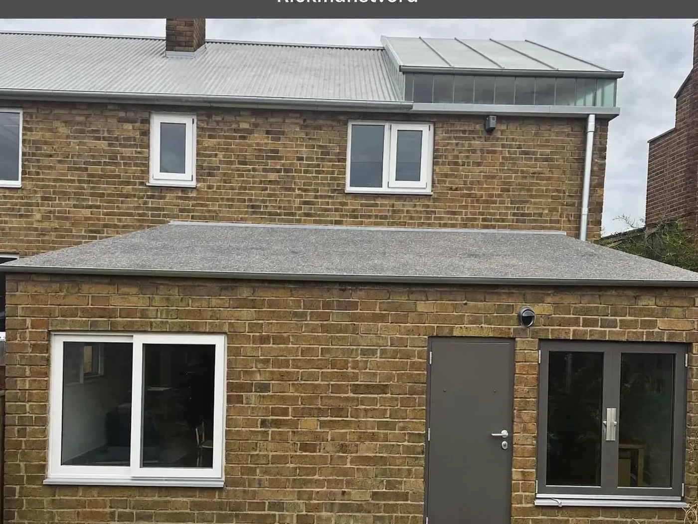 Rickmansworth: L-shaped brick extension wrapping around the back and side of a house with dark sliding doors
