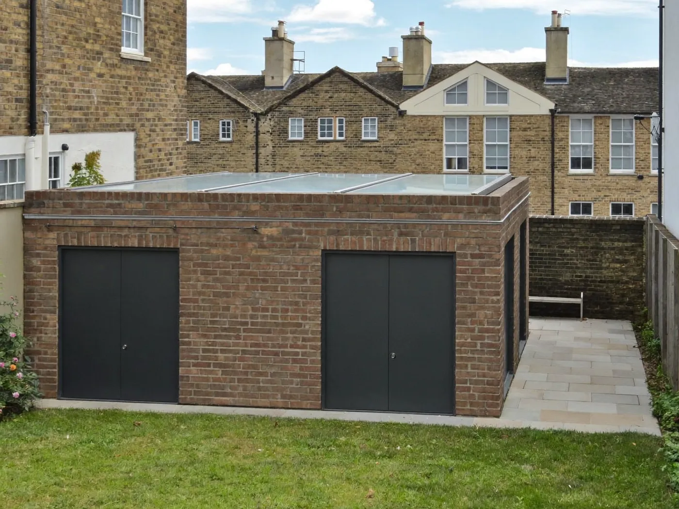 St Albans: single-storey brick rear extension with dark sliding doors onto a lawn