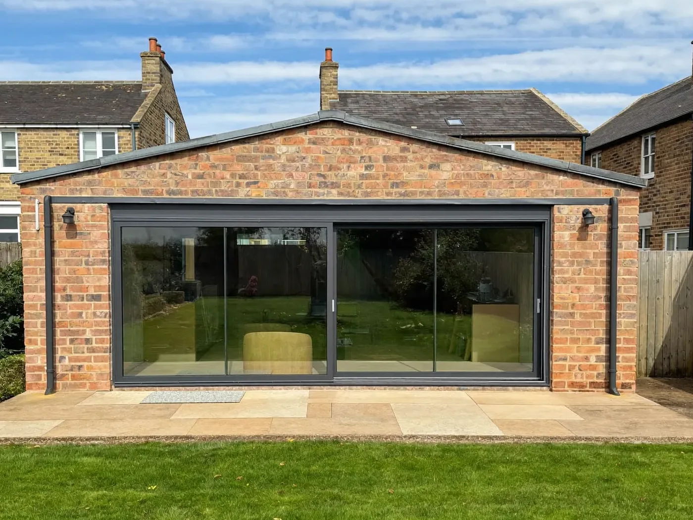 St Albans: single-storey brick rear extension with dark sliding doors onto a lawn