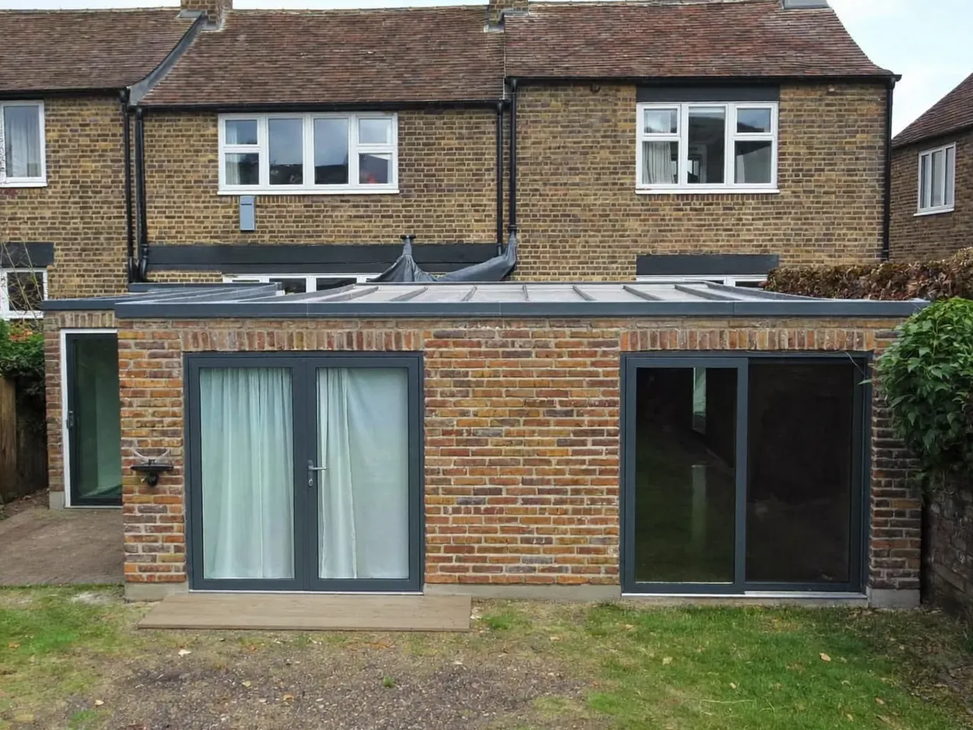 St Albans: single-storey brick rear extension with dark sliding doors onto a lawn