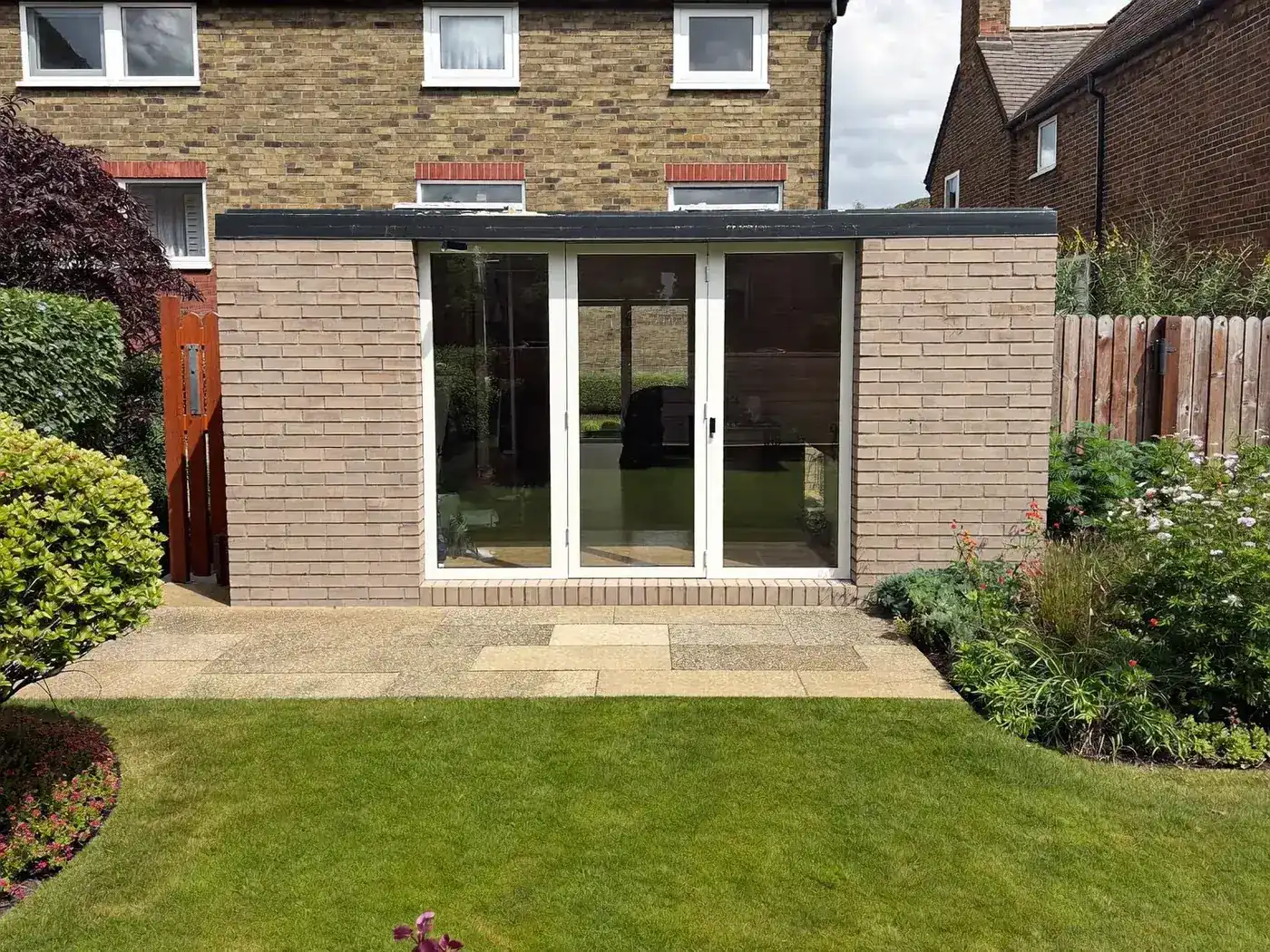 Staines-upon-Thames: single-storey brick rear extension with dark sliding doors onto a lawn