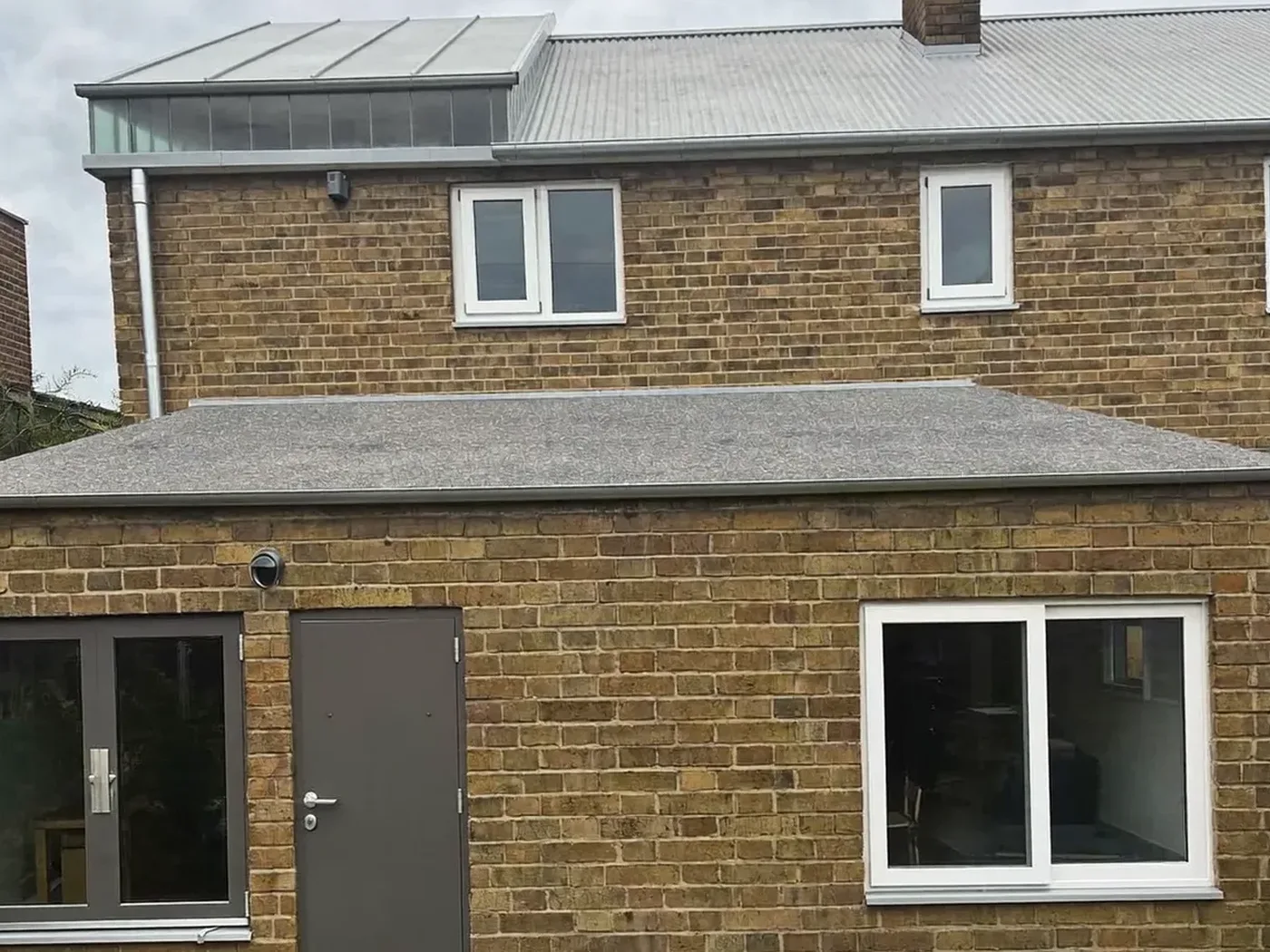 Staines-upon-Thames: L-shaped brick extension wrapping around the back and side of a house with dark sliding doors