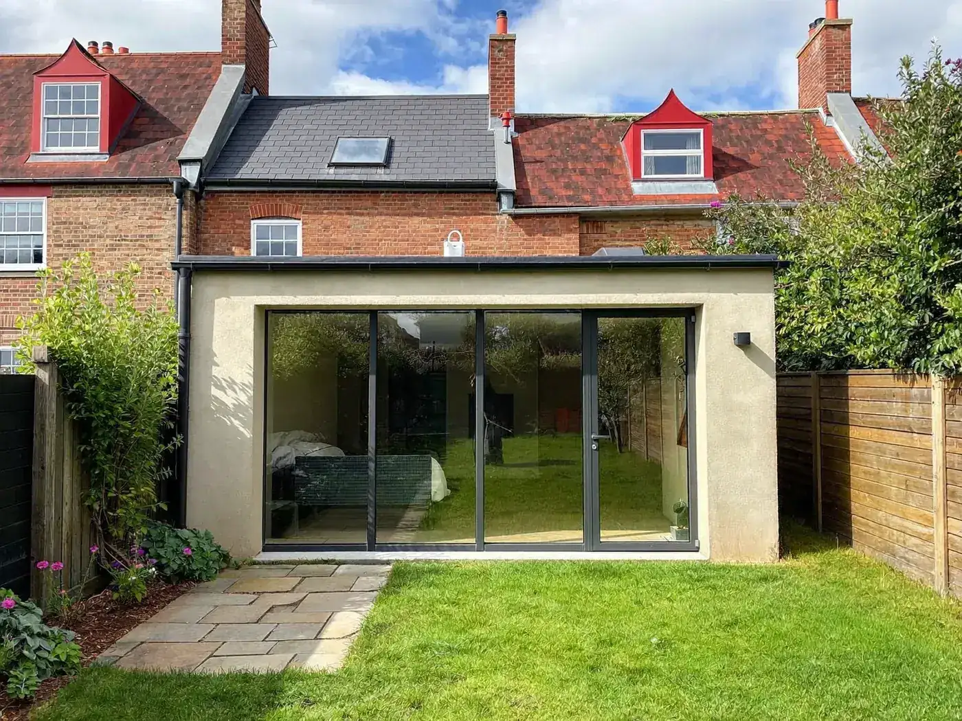 Sutton: single-storey brick rear extension with dark sliding doors onto a lawn