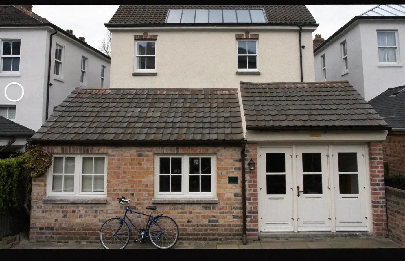 Two-bay brick extension with clay-tiled pitched roofs and white French doors