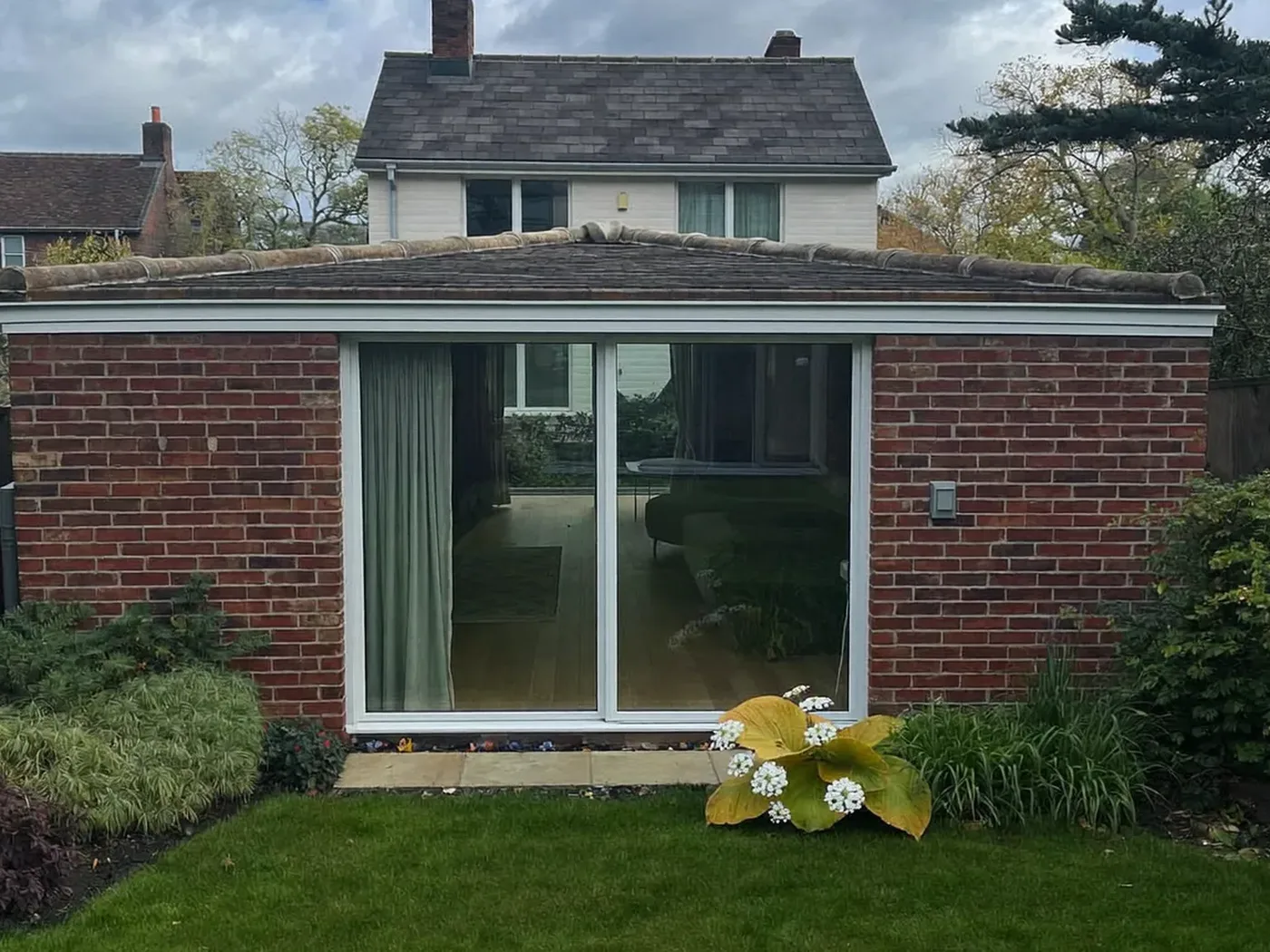 Waltham Forest: single-storey brick rear extension with dark sliding doors onto a lawn