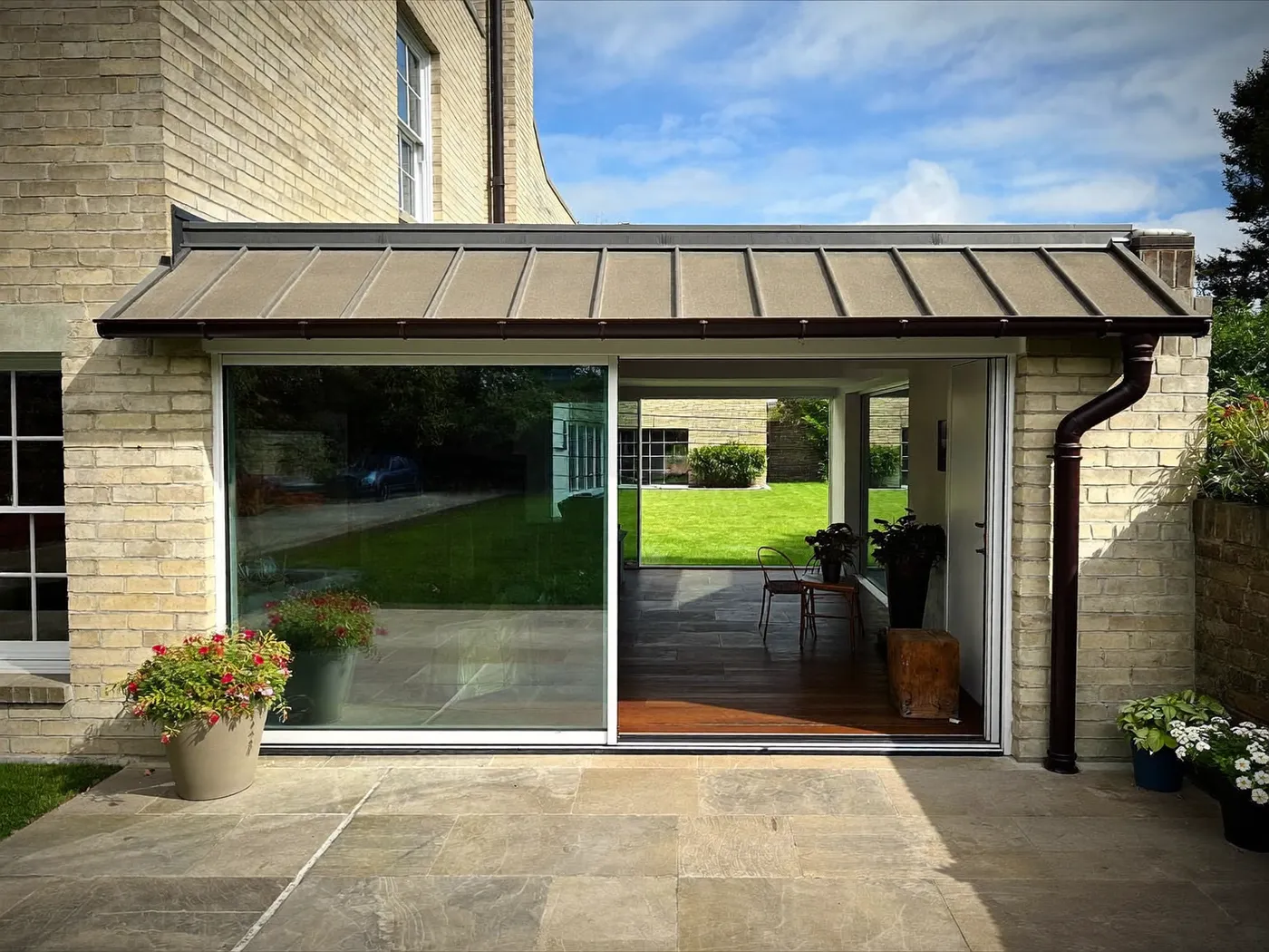 Watford: single-storey brick rear extension with dark sliding doors onto a lawn