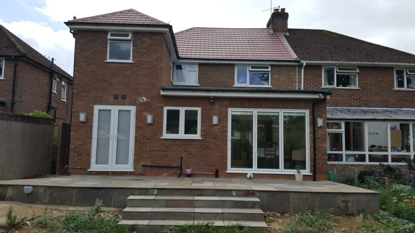 Single-storey brick rear extension with a flat roof, double doors and a tiled house behind
